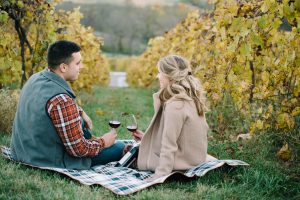 A young couple enjoy Bluemont Wine in the fall colored vines at the edge of the Blue Ridge Mountains