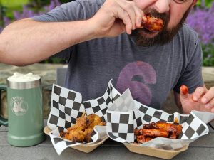 Man eating chicken wings at Father's Day king of the wing event on Father's Day at dirt farm brewing
