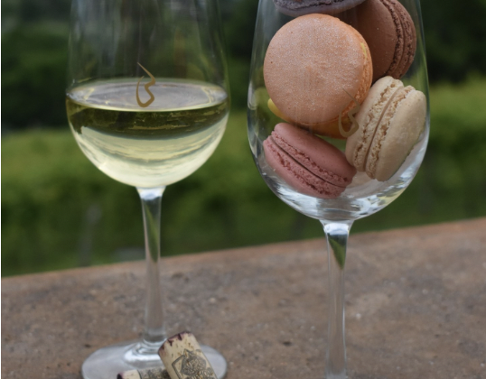 Two wine glasses filled with wine and macarons.