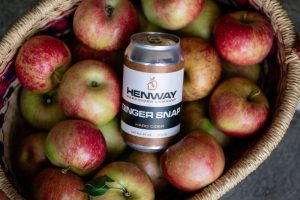 Basket of apples with cider can resting on top 