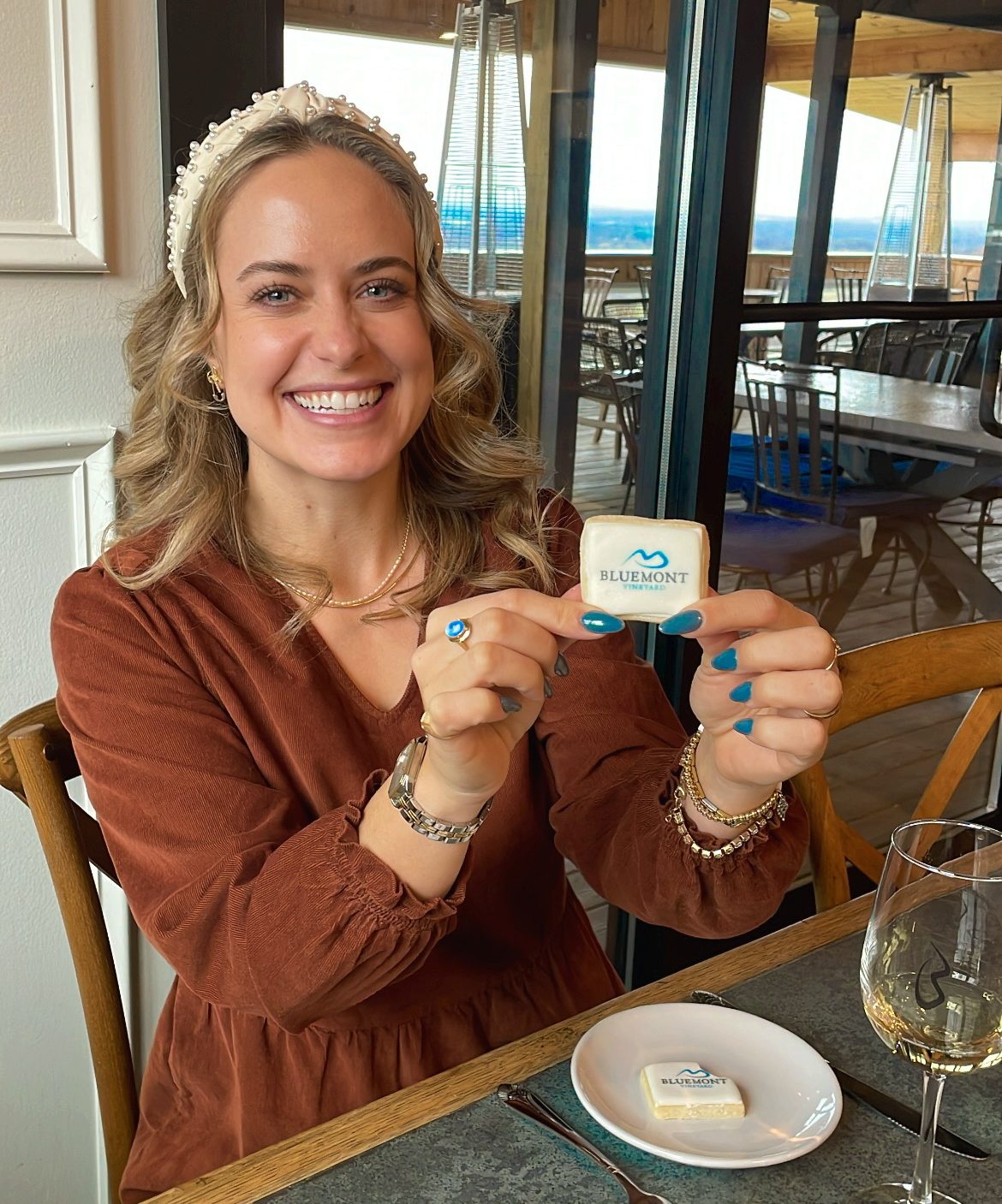 Christmas cookie & wine tasting photo. Woman holding up Christmas cookie with wine on table in front of her