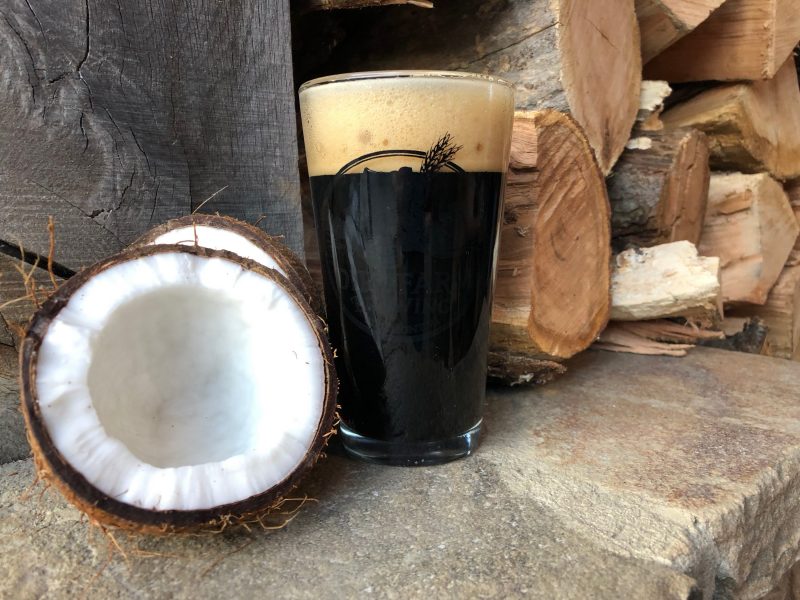 Pint of dirt farm brewings coconut milk stout staged next to a coconut in Loudoun county virginia