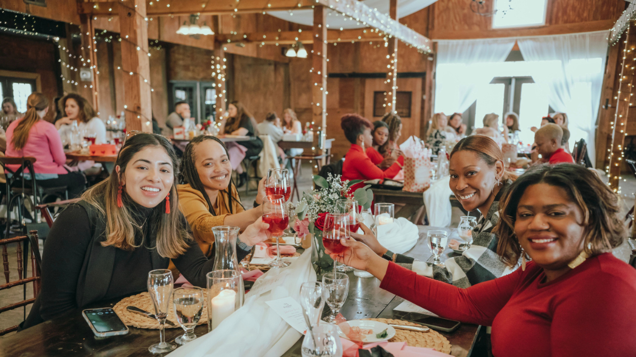 Galentine's Day Brunch main image. Woman wearing reds and pinks at the brunch table in The Stable