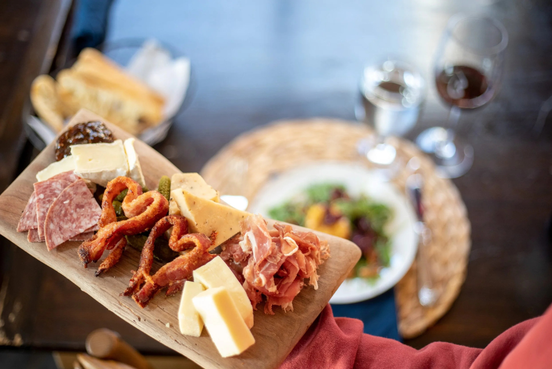 Valentines Chef's Table main image. A platter of meats & cheese held over a dinner place setting