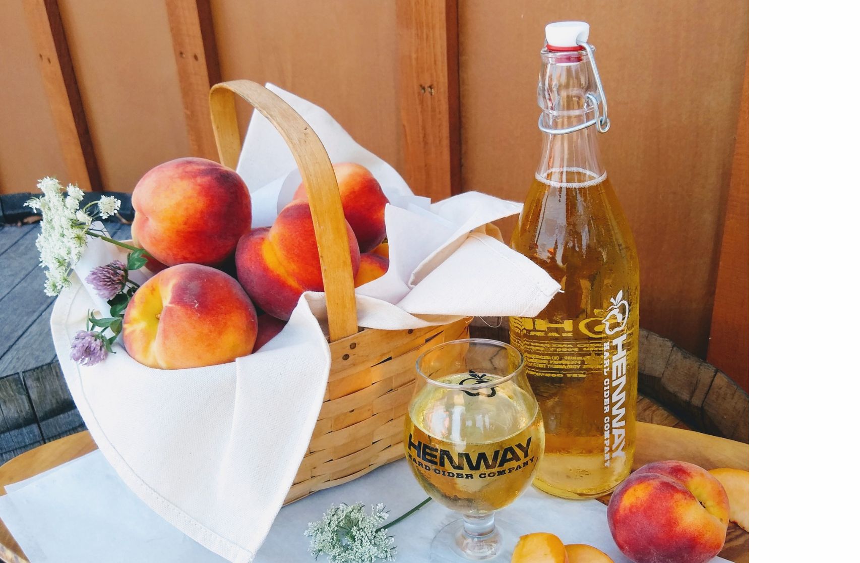 Basket of peaches with peach hard cider at Henway Hard Cider Barn