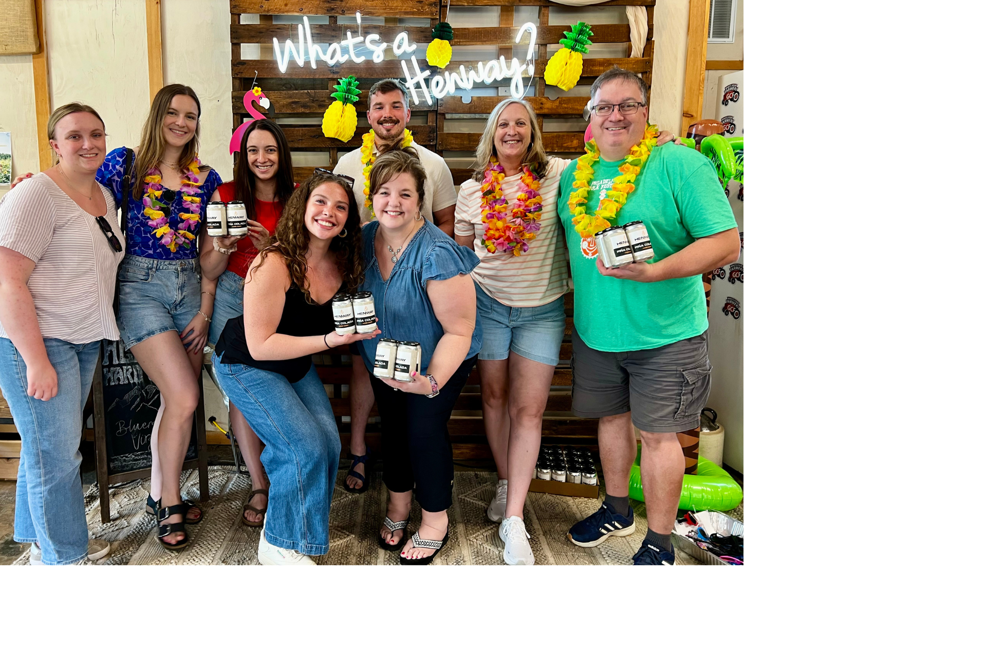 A group of people gathered in beachy attire at Henway Cider Barn's Piña Colada Party.