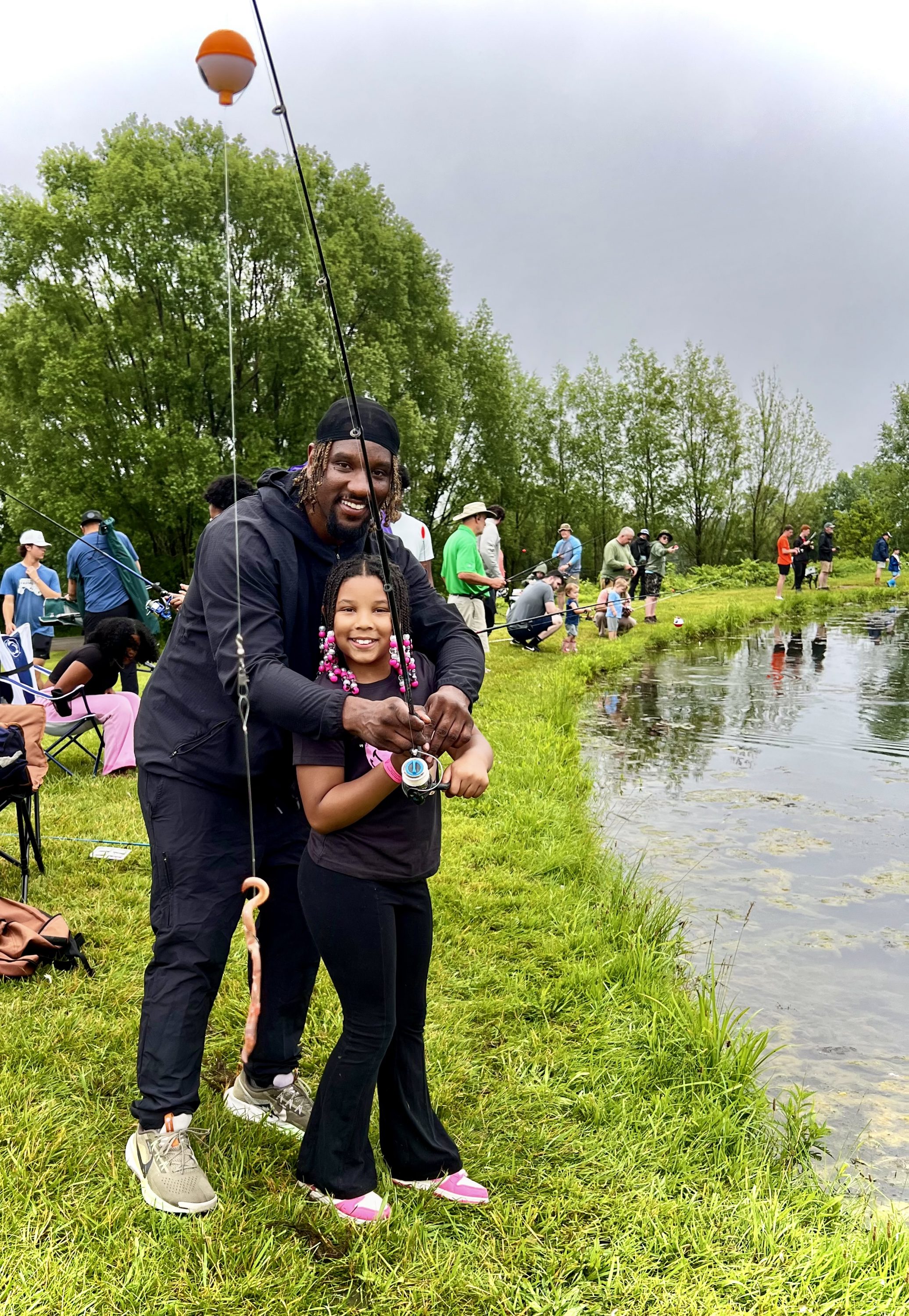 Father and Daughter holding fish at Father's Day Fishing Contest. Outside by pond at Henway Cider Barn