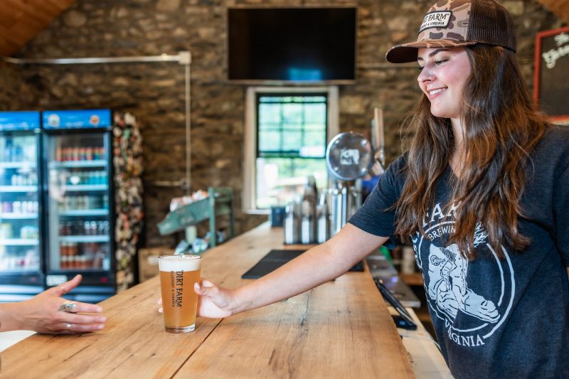 Server at Dirt Farm Brewing passing a beer to a customer during health care appreciation days
